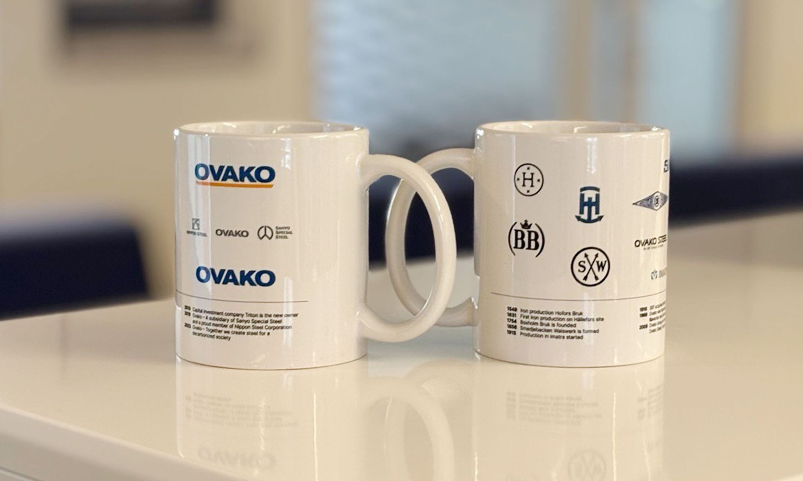 Ovako mugs with the history of logos on a table